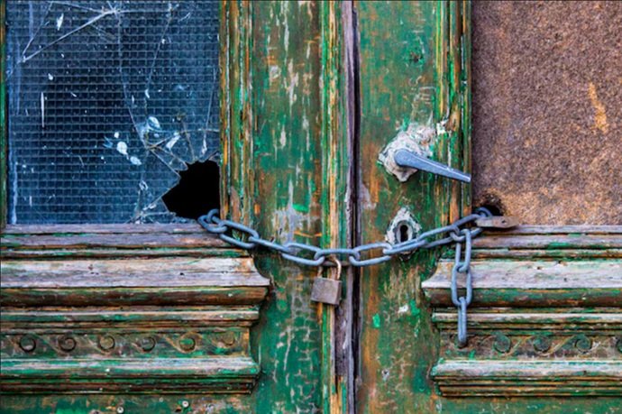 Puerta de vivienda vulnerable y ocupada, asegurada con cadena, ilustrando el riesgo que Cerrajería Reyes Sabadell previene
