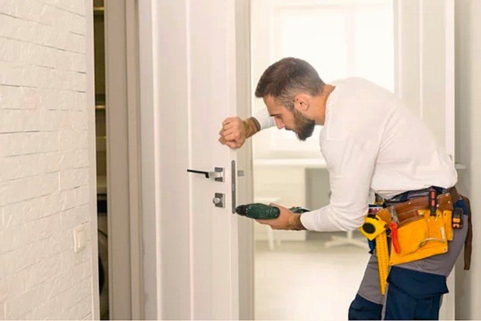 Operario técnico de Cerrajería Reyes realizando conversión en puerta residencial para inserción de escudo acorazado de alta gama.