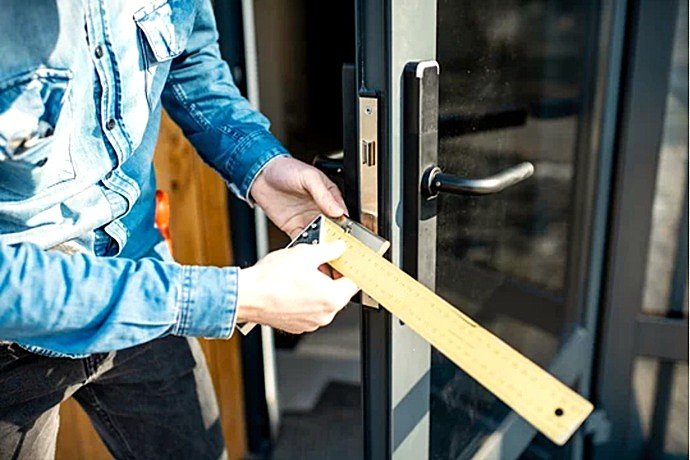 Técnico cualificado de Cerrajería Reyes tomando medidas de precisión para instalar una cerradura de seguridad.