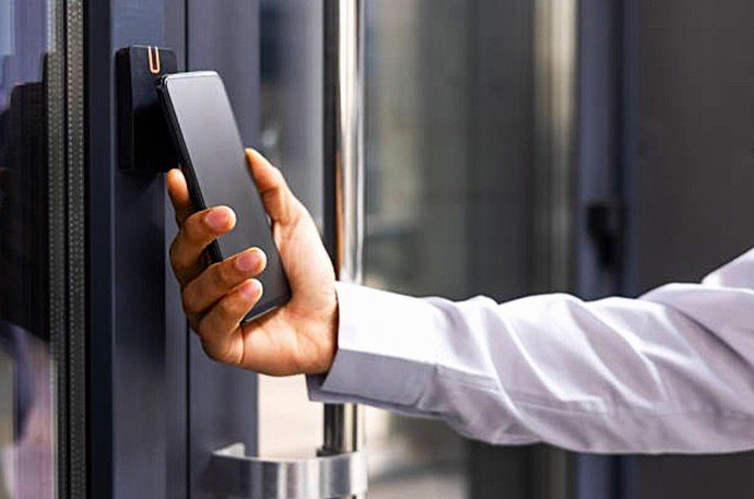 Usuario utilizando smartphone para apertura de puerta inteligente con cerradura por sistema domótico sin contacto en viviendas del Vallès Occidental.