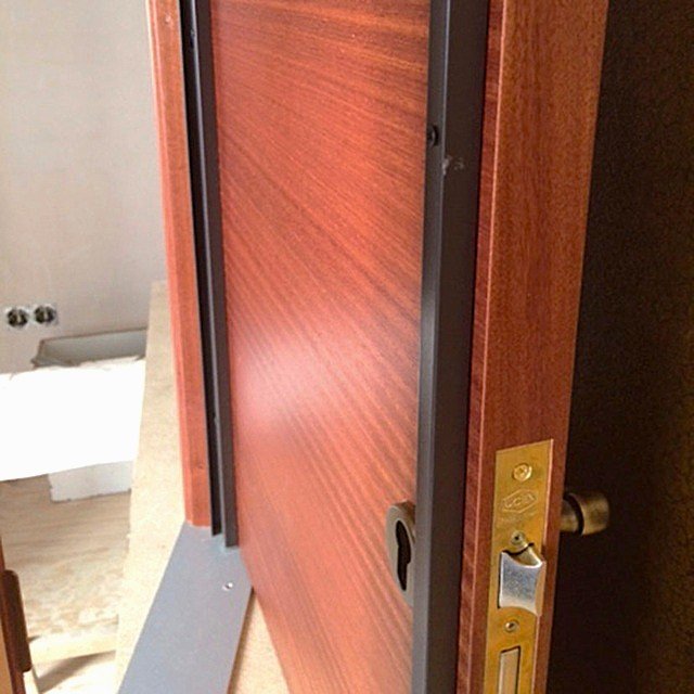 Ajuste milimétrico de cerradura multipunto de alta gama y refuerzo de acero en una puerta de madera reconvertida en blindaje de grado 4.