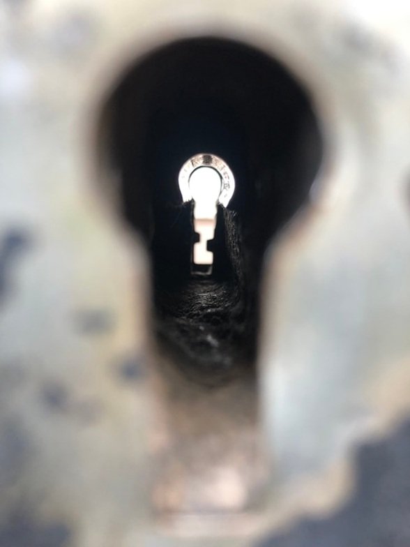 Vista macro del canal interno de un mecanismo de seguridad donde se aprecian las acumulaciones de suciedad y el paso del tiempo.