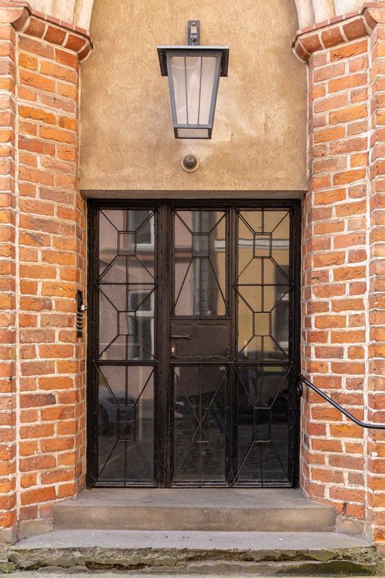 Puerta comunitaria de rejería negra integrada en fachada de ladrillo tradicional en el centro histórico de Sabadell.