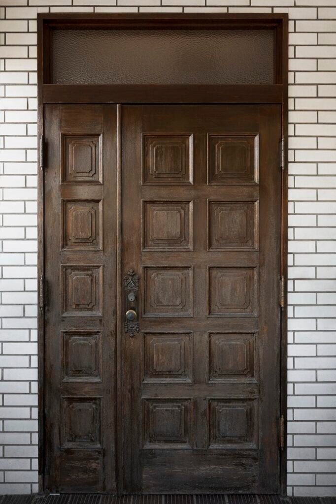 Puerta blindada antigua en Sabadell que presenta una estructura de madera vulnerable y herrajes obsoletos sin protecciones actuales.