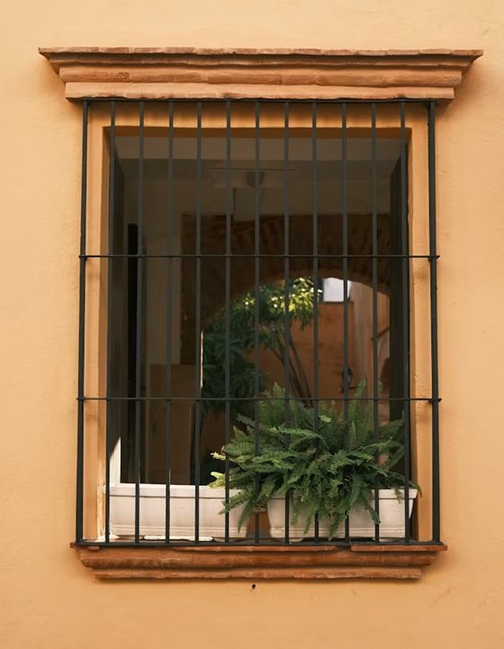 Reja fija de diseño tradicional en ventana de Sabadell que protege el acceso respetando la estética clásica de la edificación.
