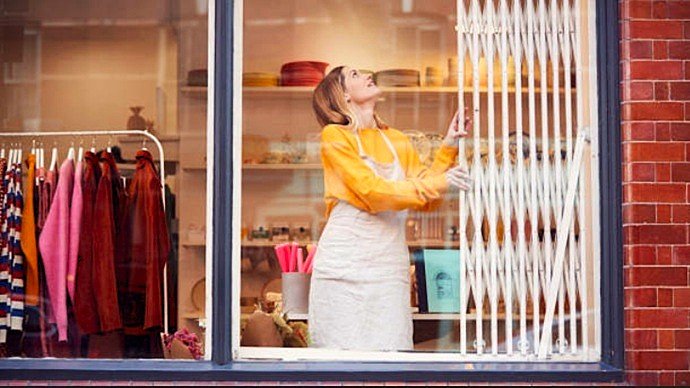 Comerciante abriendo reja de ballesta blanca articulada en escaparate de tienda en Sabadell.