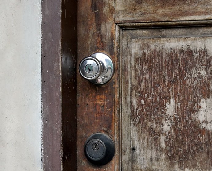 Puerta de madera con cerradura antigua desgastada por el uso en piso de alquiler en Sabadell.